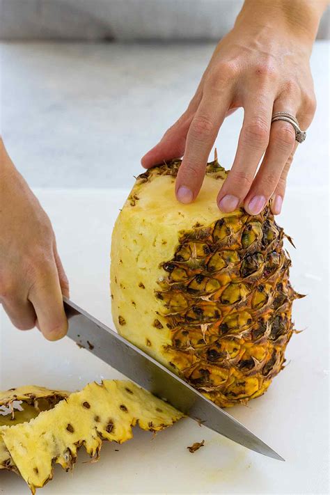 Halve the pineapple. Set the pineapple on the cutting board with the flat side down. Use a sharp knife to slice through the length of the pineapple down the middle. Cut the pineapple halves in half again. With the flat cut side down, run the knife through the two pieces lengthwise to create four quarters. 